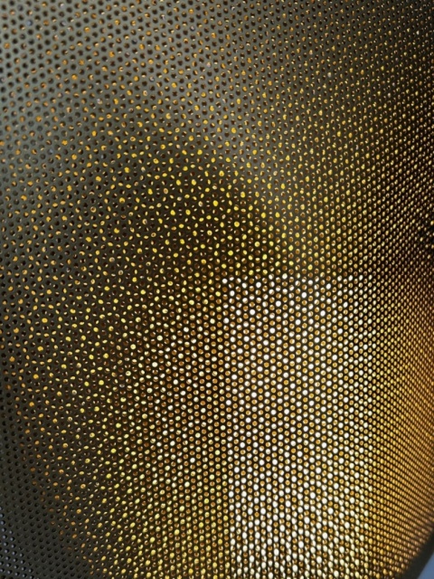 Detal perforowanej powierzchni metalowego klosza.