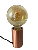 Żarówka Globe L zamontowana w miedzianej oprawie lampy stołowej.